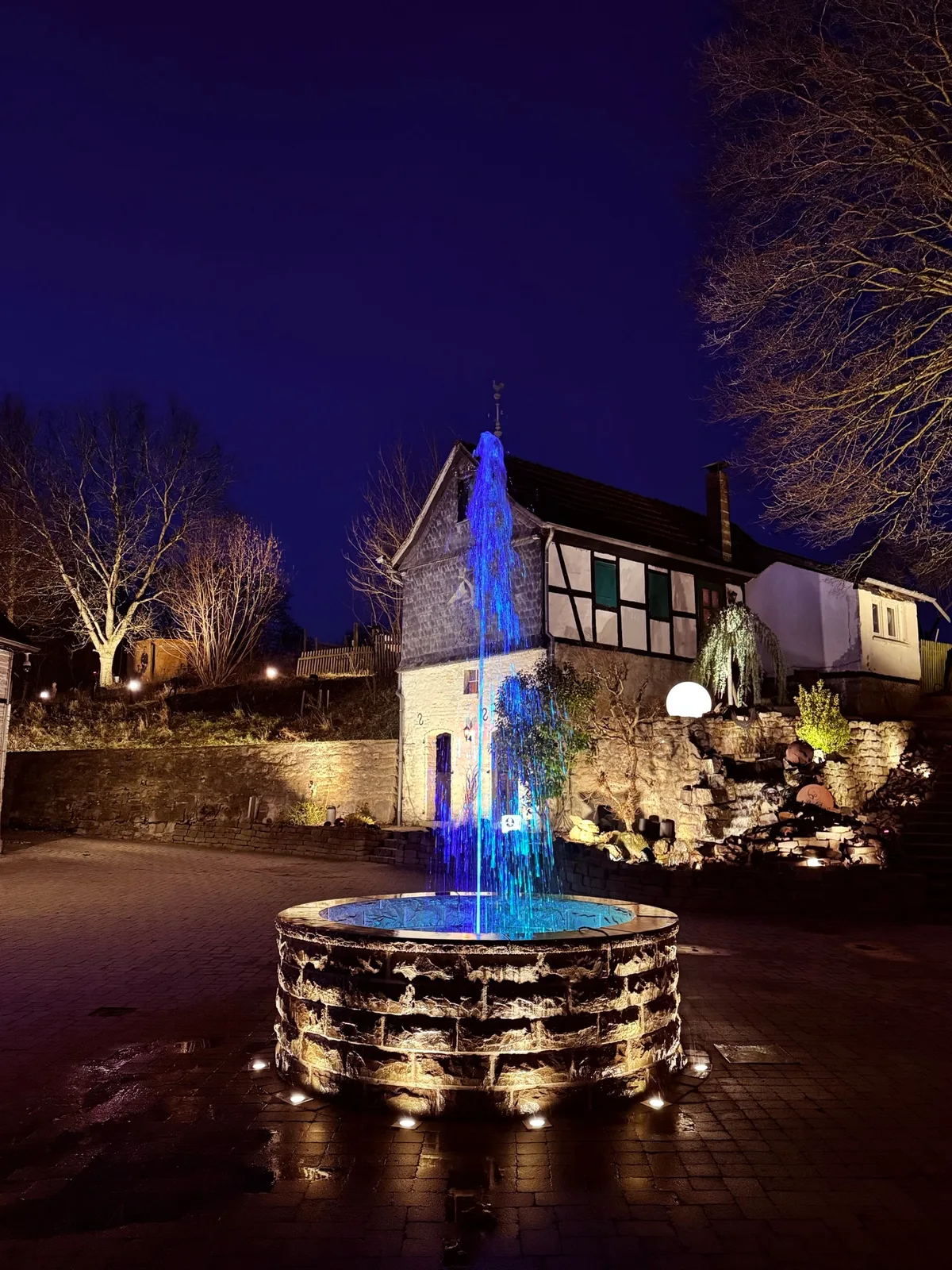 Gut Asselborn und der beleuchtete Brunnen am Abend.